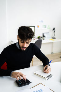 Businessman using calculator at desk in office