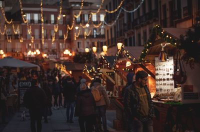 People walking on illuminated street in city at night