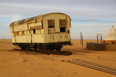 Abandoned train on beach against sky