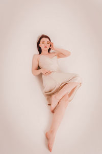 Portrait of young woman standing against white background