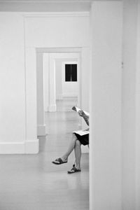 Low section of woman with magazine sitting in corridor