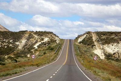 Empty road along landscape against sky