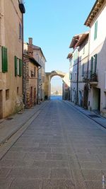 Empty alley amidst buildings in city against sky