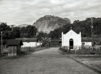 Houses by road by buildings against sky