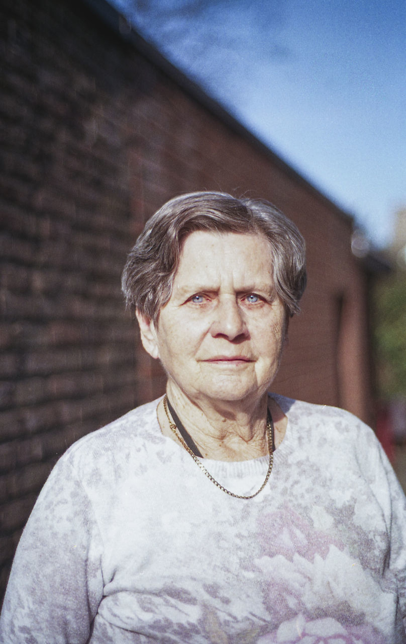 one person, adult, portrait, senior adult, person, front view, men, day, lifestyles, casual clothing, headshot, architecture, sky, human face, focus on foreground, women, waist up, standing, outdoors, looking at camera, emotion, nature, building exterior, seniors, looking, gray hair