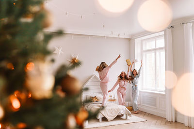 A group of cheerful female friends dance rejoice have fun in the christmas holidays in the bedroom