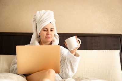 Portrait of cute girl using laptop while sitting on sofa at home