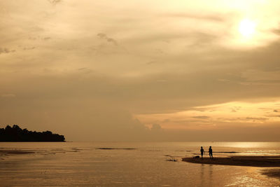 Silhouette people on beach against sky during sunset