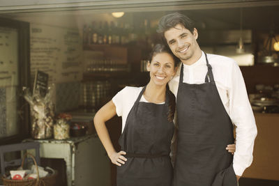 Portrait of happy business couple standing outside restaurant