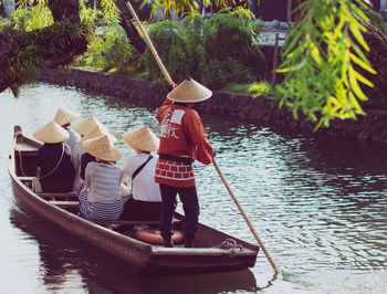 Rear view of people on boat sailing in river