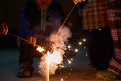 Cropped hands of people igniting sparklers