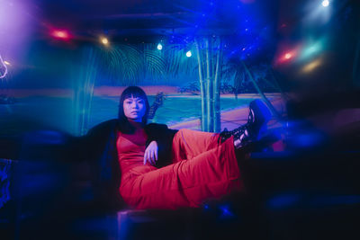 Portrait of woman sitting in illuminated nightclub