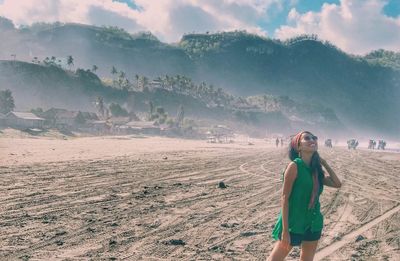 Young woman standing on land against sky