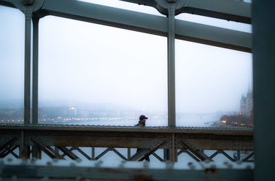 Man standing on bridge against sky