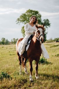 Young woman riding horse on field