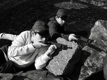 Boys shooting with toy handguns on rocks