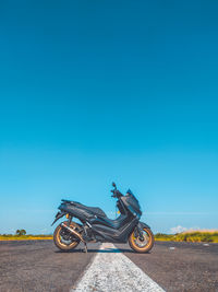 Side view of a motorcycle on road against blue sky