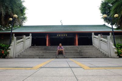 Woman walking by building against sky