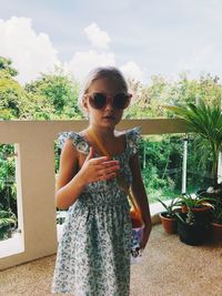 Portrait of woman wearing sunglasses standing against plants