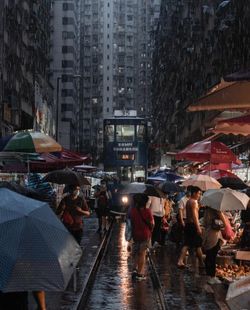 People walking on wet street in city during rainy season