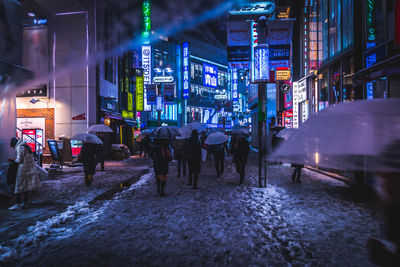 People walking in illuminated city at night