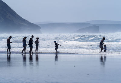 People enjoying on shore at beach against sky