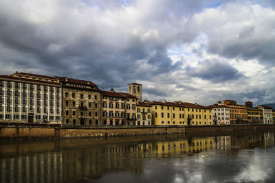 Buildings and cloudy sky reflecting in canal