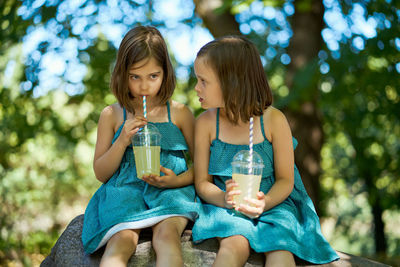 Two little girls drinking lemonade in park