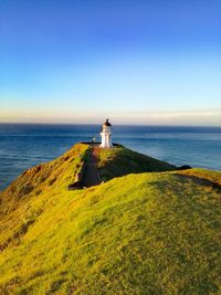 Lighthouse by sea against sky