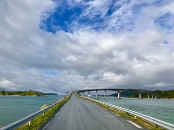 Empty road by bridge against sky