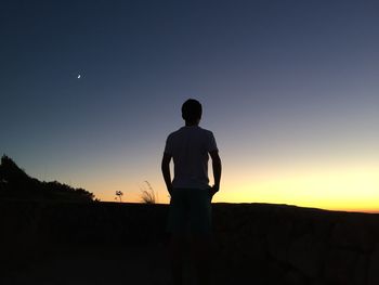 Silhouette man standing on field against clear sky during dusk