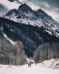 Rear view of men on snow covered field against mountain