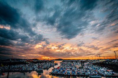 Boats moored at harbor against sky during sunset