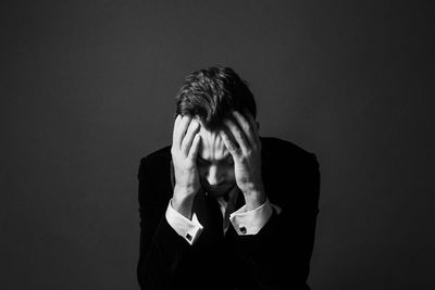 Tensed businessman sitting against gray background