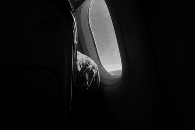 Midsection of man by window in airplane