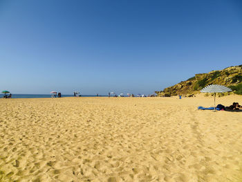 Sand by the ocean - scenic view of beach against clear blue sky