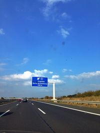 Road passing through highway against cloudy sky