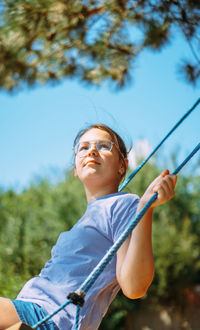 Portrait of young woman swinging at playground