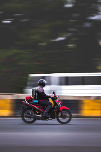 Blurred motion of man riding motorcycle on road