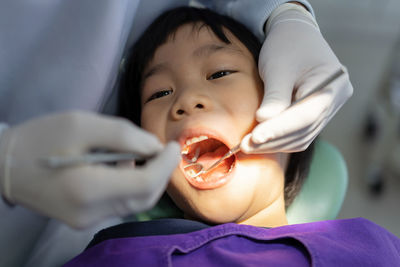 Hand of doctor dentist is working on the teeth of asian little kid patient in dental clinic