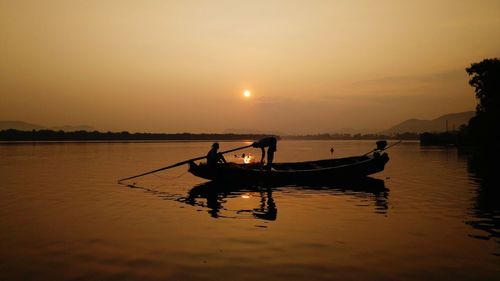 Silhouette man on boat against sky during sunset