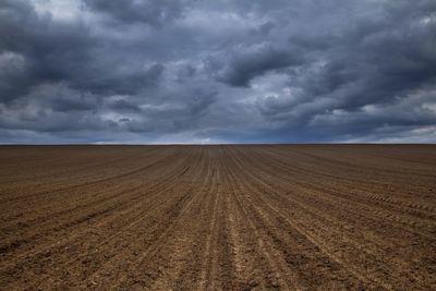 Plowed field against cloudy sky