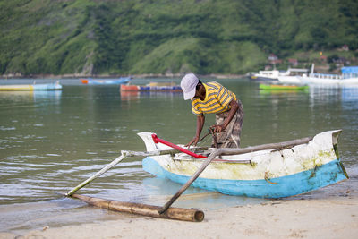 Fisherman in boat moored at lakeshore