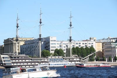 Sailboats in river against buildings in city