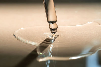 A pipette of cosmetic gel on a beige background.