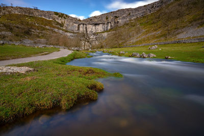 Surface level of water flowing by land against sky