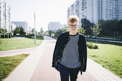 Portrait of man standing on footpath in city