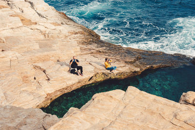 High angle view of people on rock formation at sea