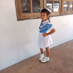 Full length of cute girl standing against wall