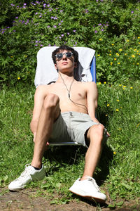 Young man wearing sunglasses sitting on grass